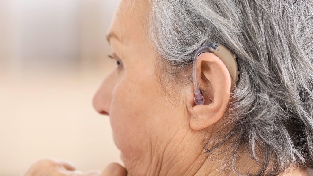 a senior woman with gray hair and a hearing aid in her ear