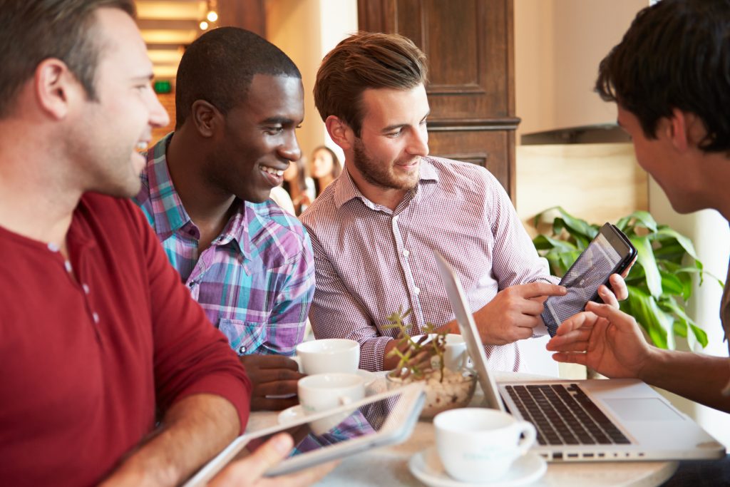 a group of young men laughing and enjoying each others company in a restaurant, looking at iPhones and iPads, computer information