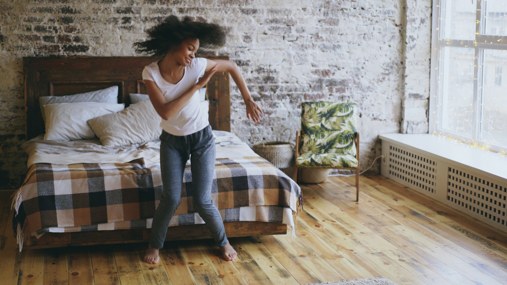 a happy, joyful young Black woman excited and dancing in her bedroom