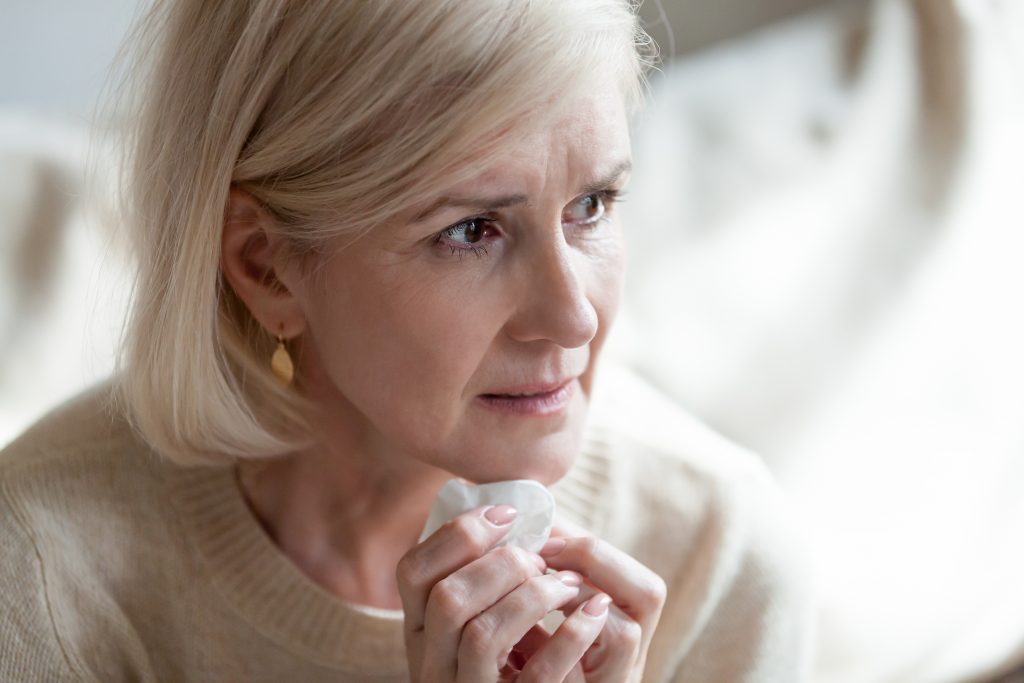 a middle aged woman holding a tissue looking worries, sad, concerned or frightened