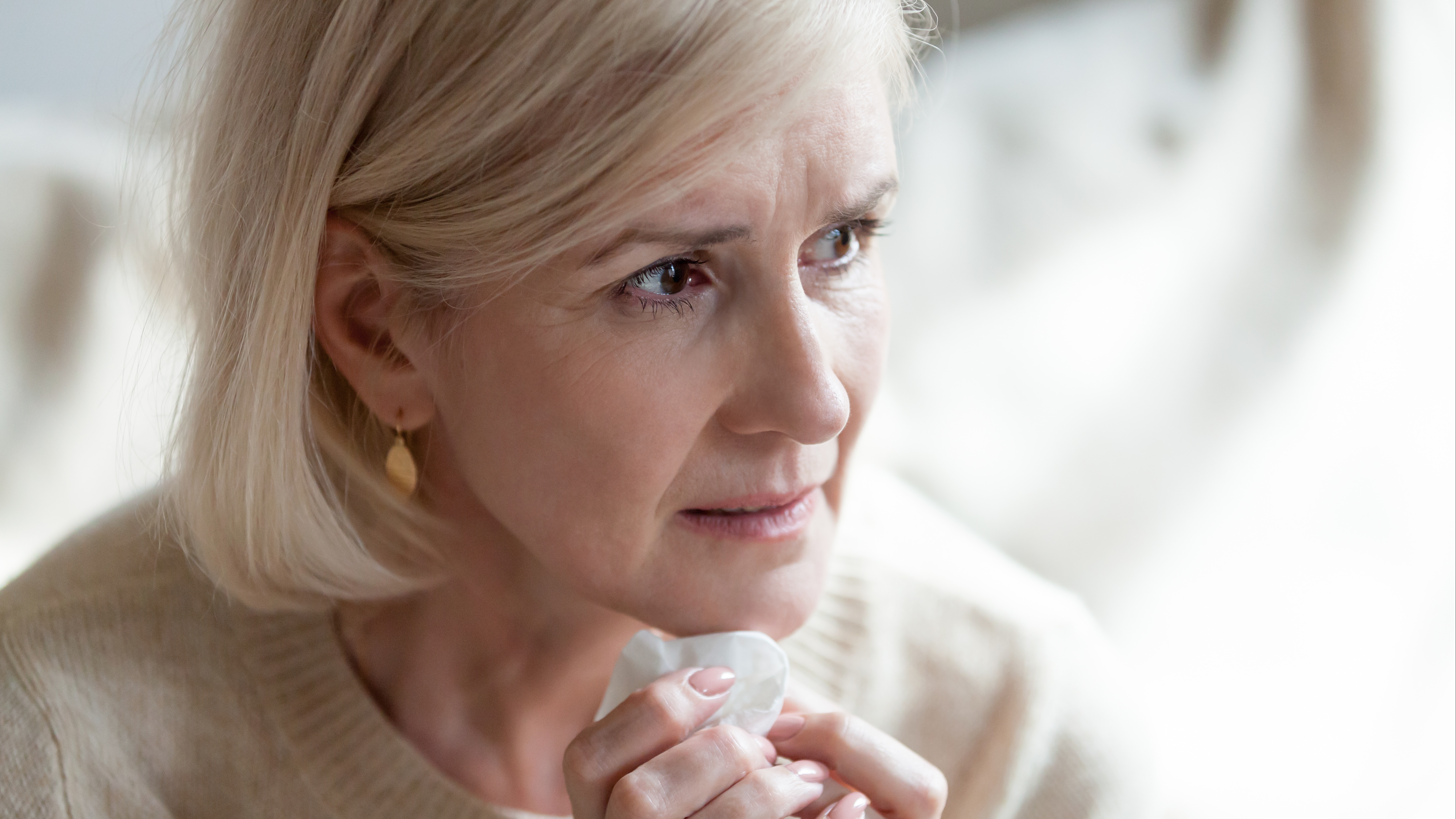 a middle aged woman holding a tissue looking worries, sad, concerned or frightened