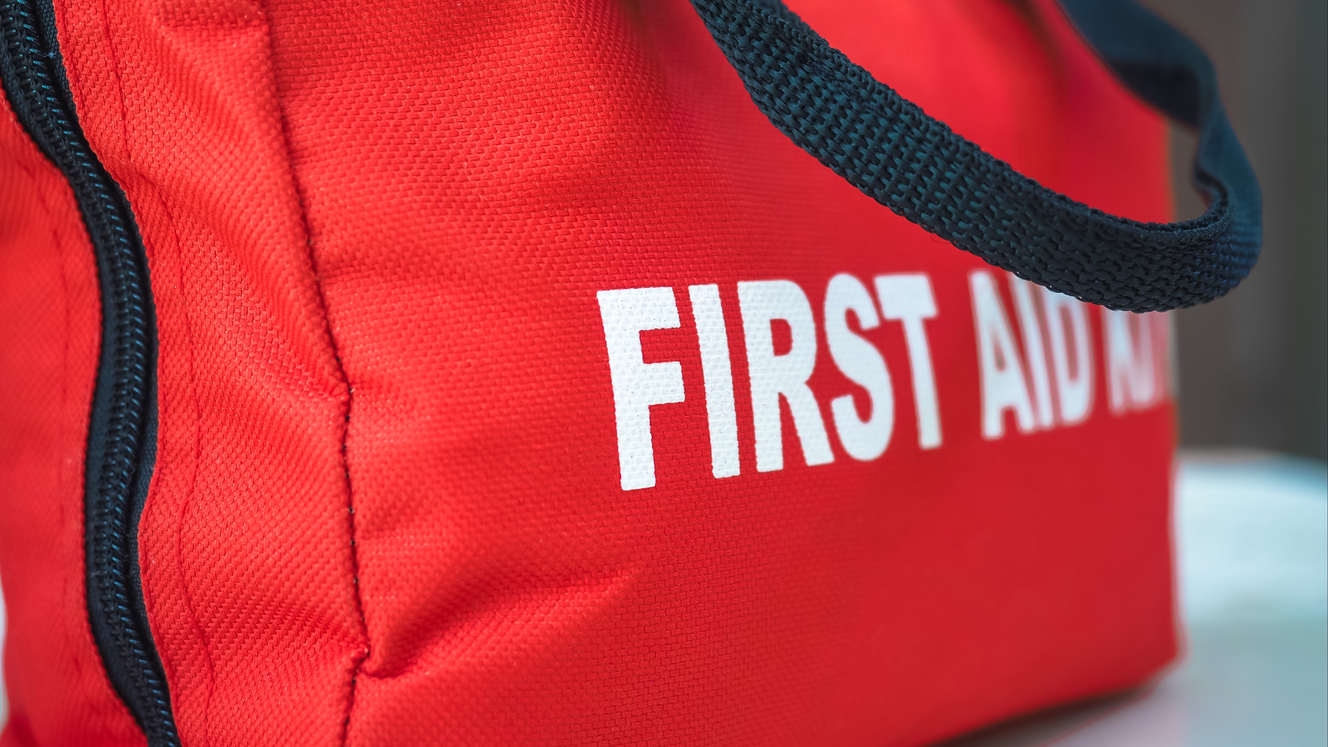 a red canvas bag with the words First Aid Kit