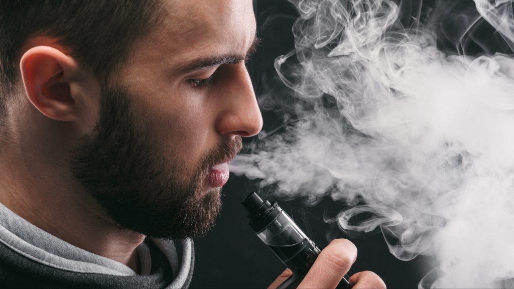 a young man exhaling from a vaping tool