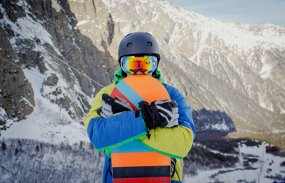 a snowboarder on a snowy mountainside, holding a snowboard