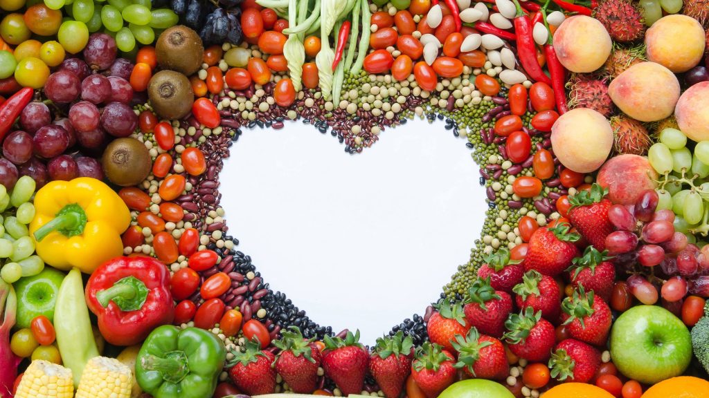 assorted fruits, vegetables and legumes arranged around a blank heart shape