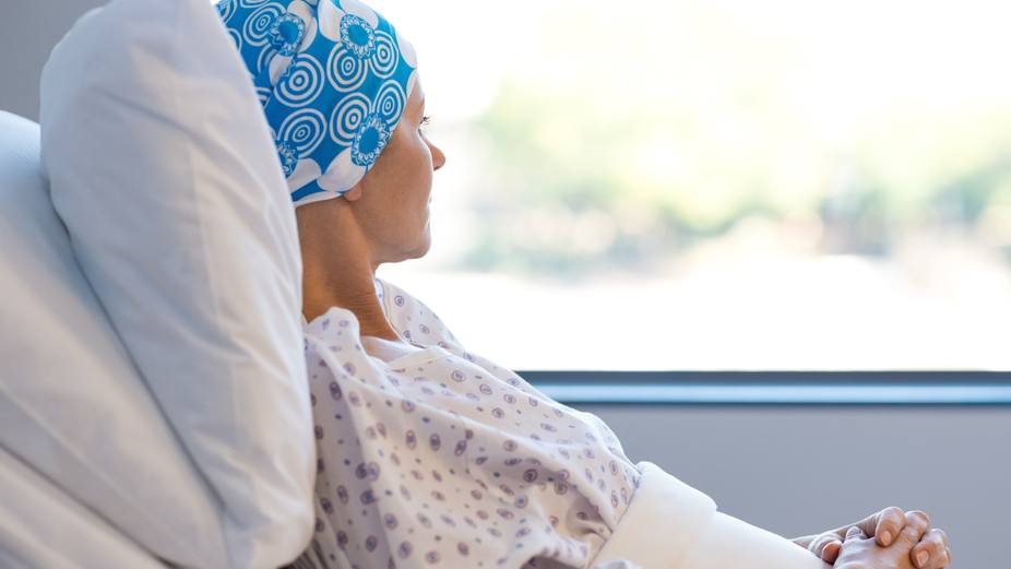 a woman, perhaps a cancer patient, in a hospital bed looking out the window, looking thoughtful and peaceful