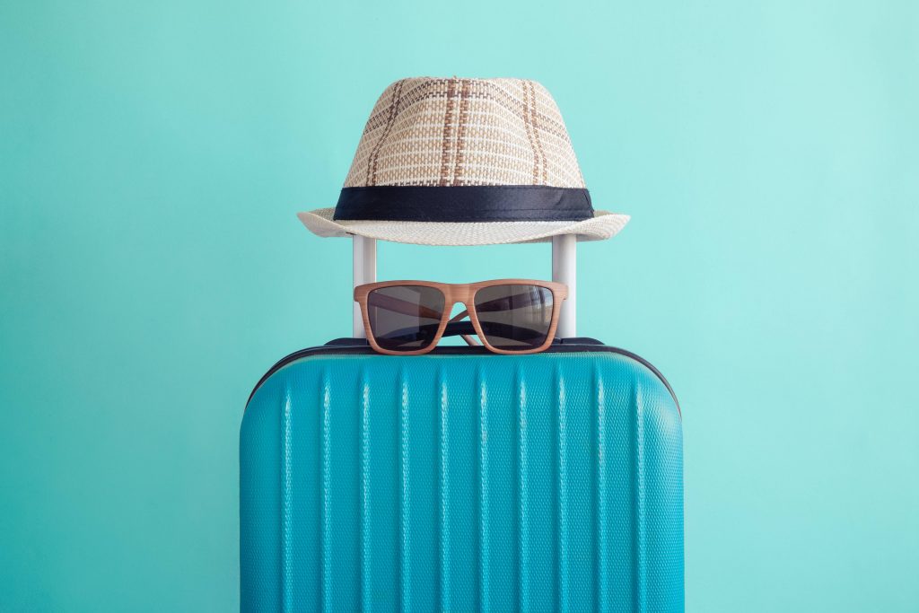 a suitcase with a hat and pair of sunglasses