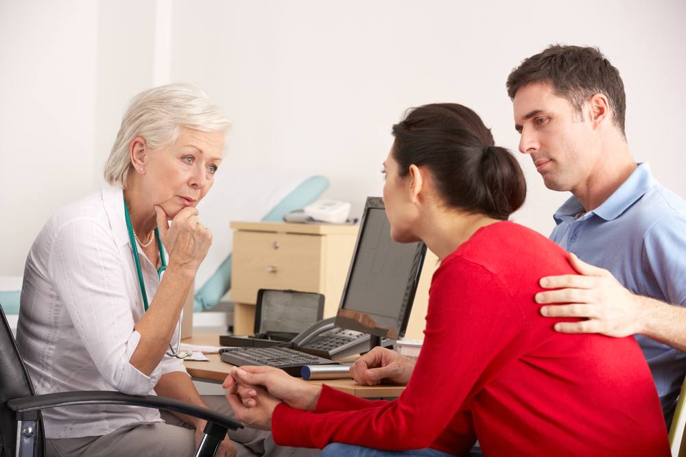 a worried middle-aged couple talking with a health care provider in her office