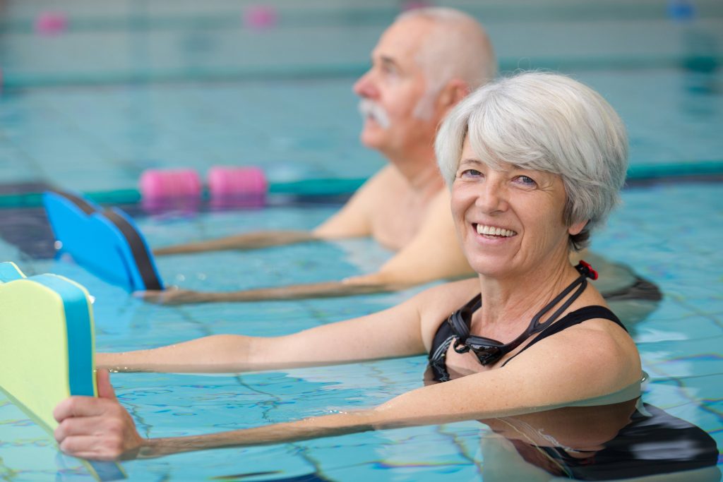 a smiling older woman in the pool in a swimming or water fitness class