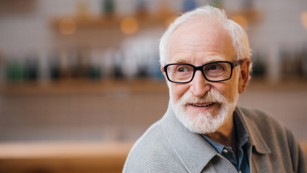 Un acercamiento de un hombre mayor con cabello y barba blanca que usa lentes