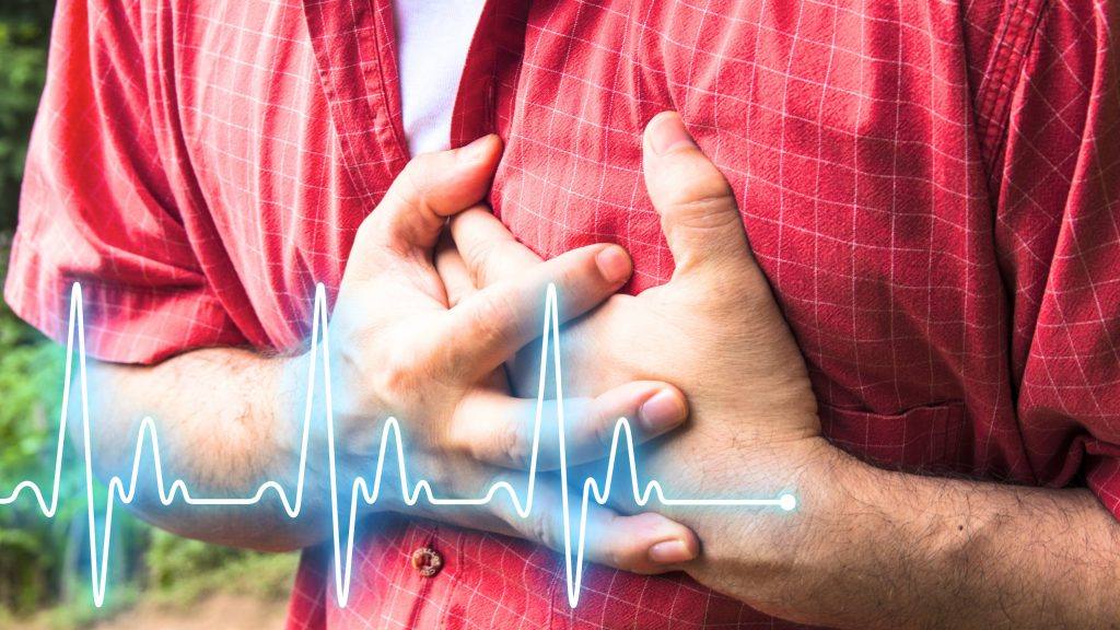 Un hombre con camisa roja se lleva las manos al pecho porque siente dolor o sufre un ataque cardíaco