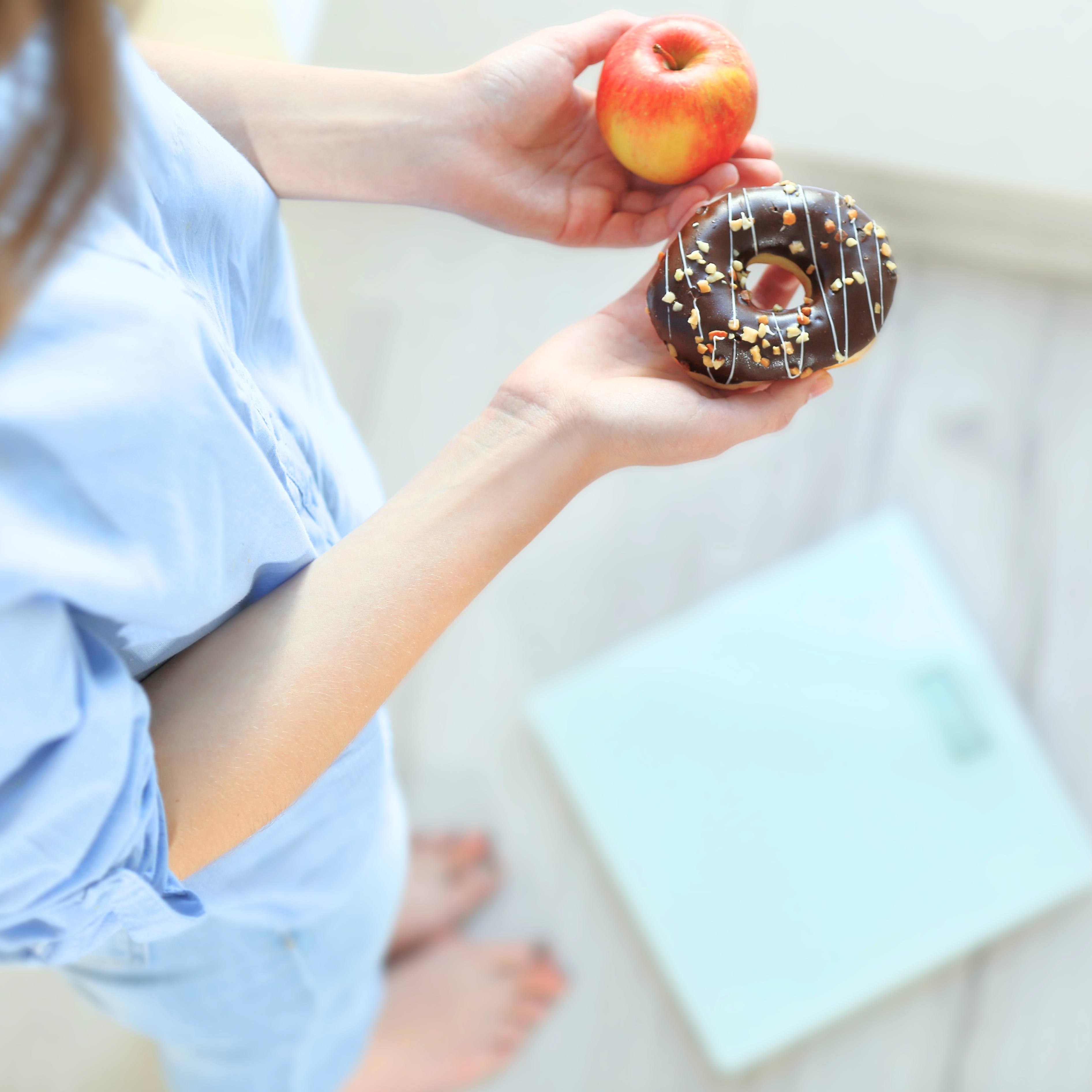 https://newsnetwork.mayoclinic.org/n7-mcnn/7bcc9724adf7b803/uploads/2020/02/a-woman-holding-an-apple-in-one-hand-a-sprinkled-donut-in-the-other-while-standing-near-a-scale-to-weigh-herself-1x1-1.jpg