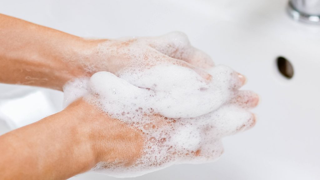 Una persona se lava las manos con agua y jabón en un lavabo
