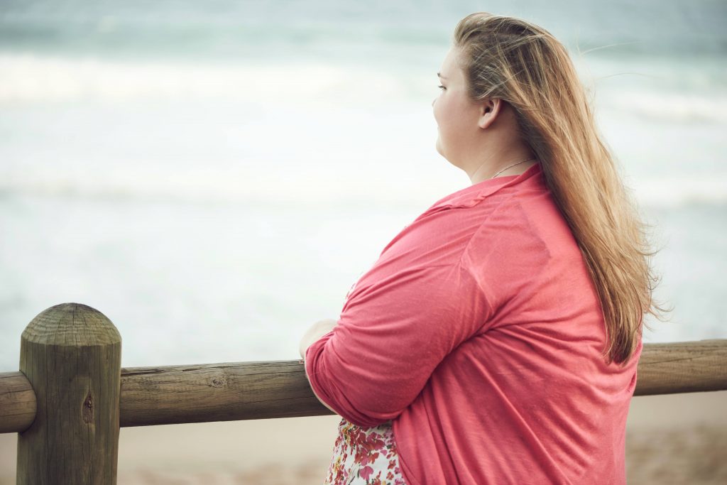 young overweight obese woman looking out at the ocean