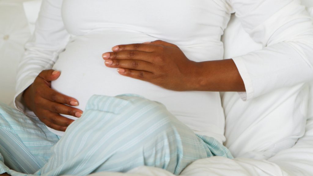 Una mujer embarazada se lleva las manos al vientre
