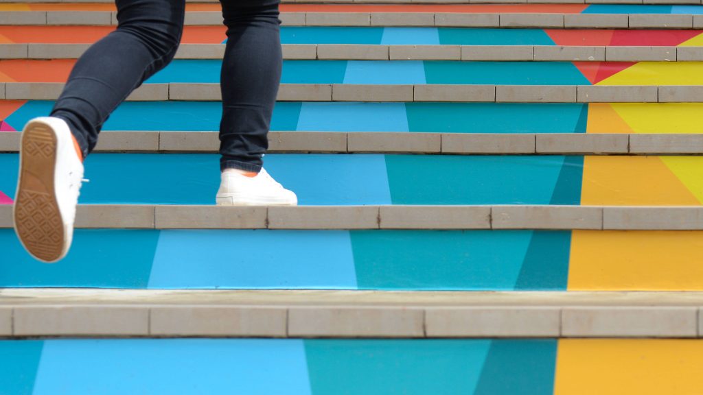 a close-up of a person's lower legs and feet walking up a colorful set of stairs
