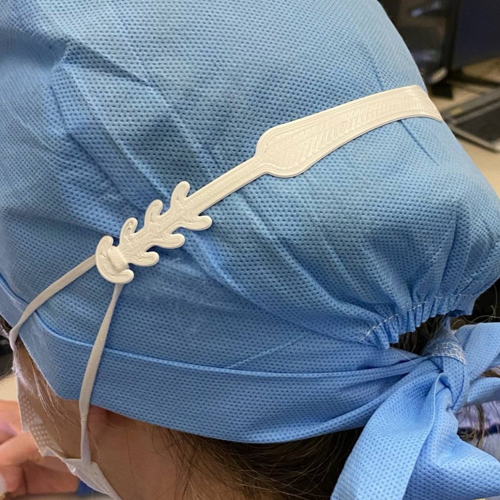 a nurse or a medical researcher with a blue scrub cap and wearing a white ear loop mask attachment