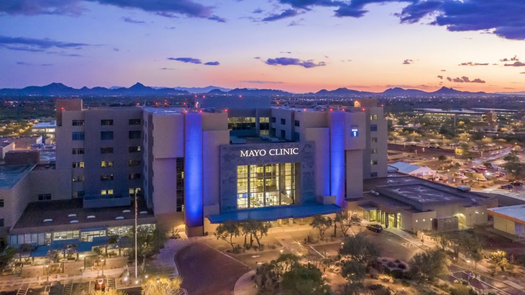 the Mayo Clinic Arizona campus at sunset with symbolic blue lighting in the front of the building