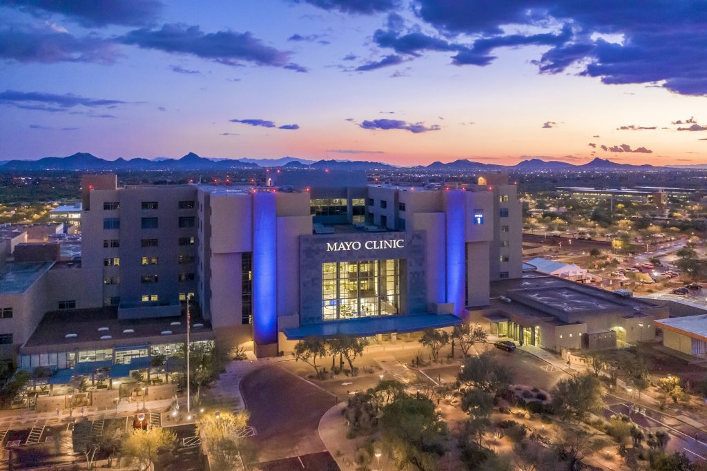 Skyline of the Mayo Clinic Hospital in Arizona with the sun setting behind the mountains in the background.