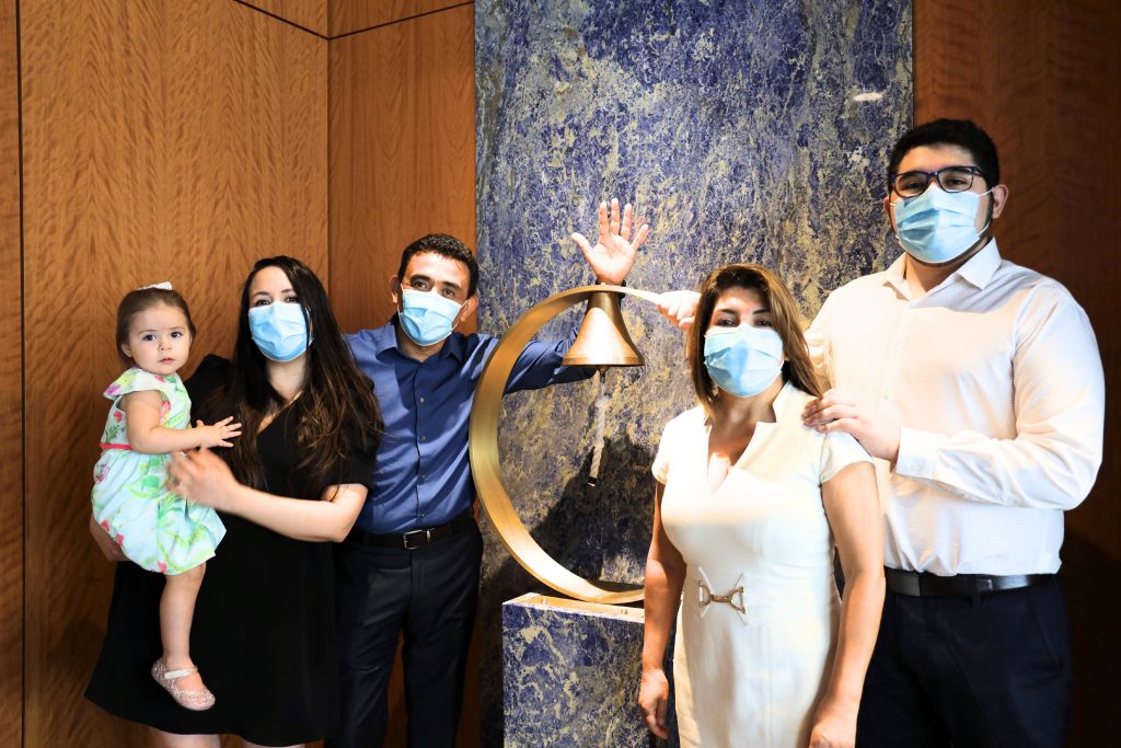 Eduardo Agüero, paciente de cáncer de Mayo Clinic Florida, con su familia después del último tratamiento de quimioterapia, todos con mascarillas protectoras, mientras toca el timbre porque su tratamiento ha terminado
