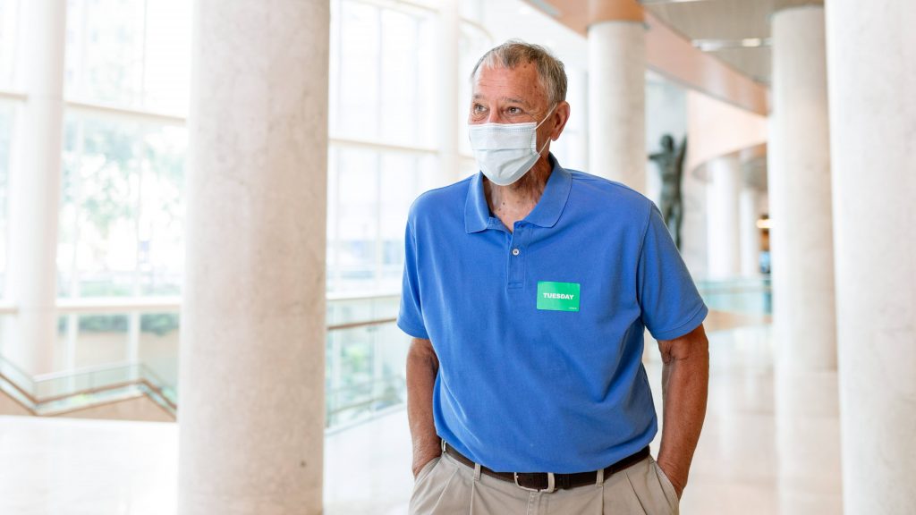 Mayo Clinic throat surgery patient James (Jim) Koski in a blue shirt and wearing a face mask while walking through the Gonda Lobby