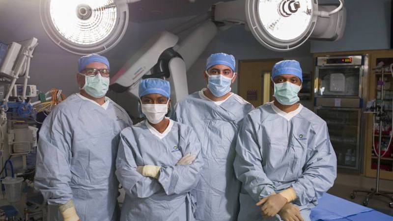 a group of diversity Mayo Clinic medical staff in surgical gowns, face masks and gloves, PPE, standing together in an operating room