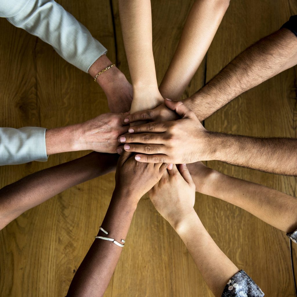 a circle of people's hands and arms coming together as a diverse community like a work team