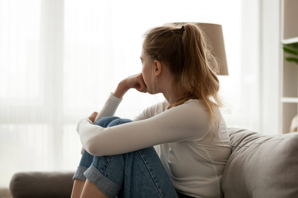 Adolescent teen sad depressed in pain nervous thinking sitting on couch