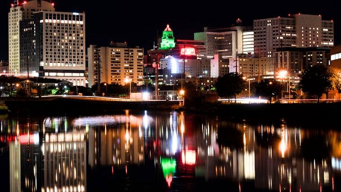 the Rochester MN night skyline with the Plummer Building highlighted in mostly green and red lights in celebration of Juneteenth Day