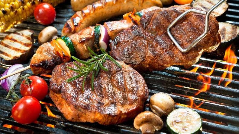 a grill filled with picnic foods like hamburgers, steaks, brats and vegetables