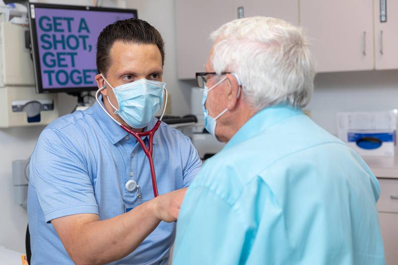 Mayo Clinic Health System physician wearing a mask and examining a patient, both are white males