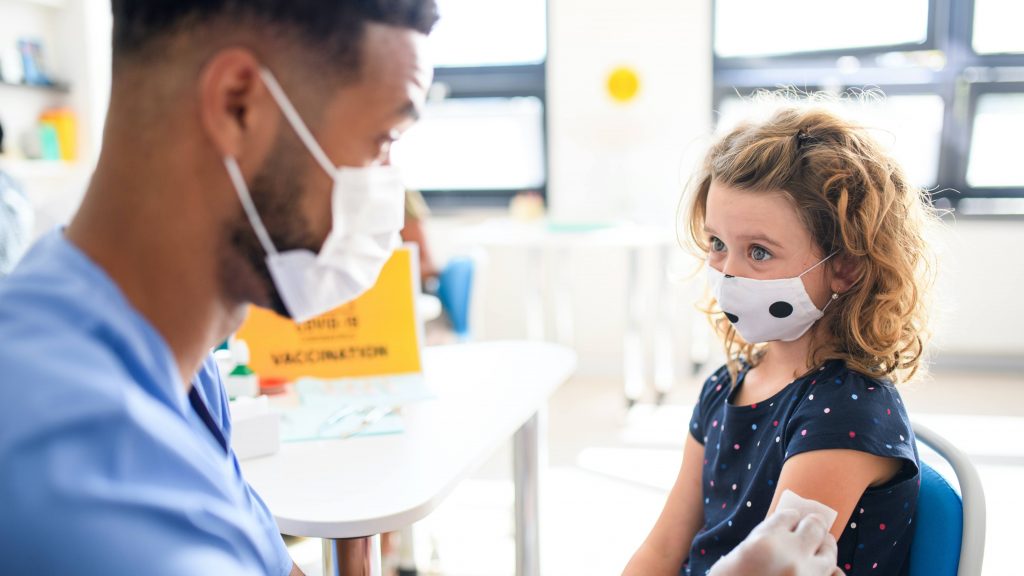 a young white girl wearing a mask and getting a vaccine
