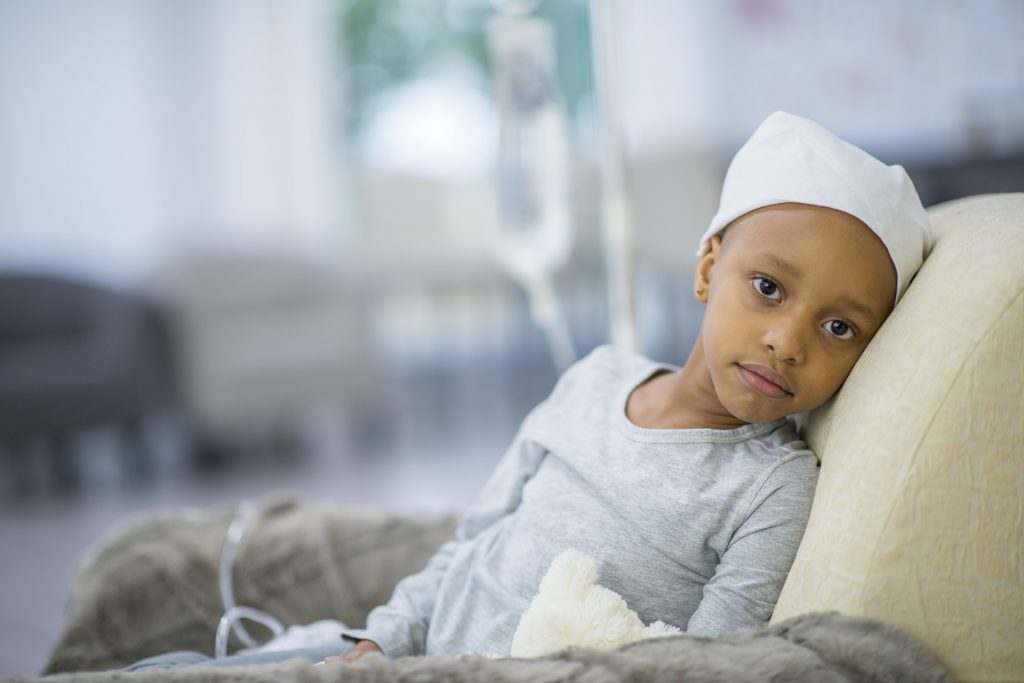a young Black child in the hospital with an IV, perhaps sick with cancer