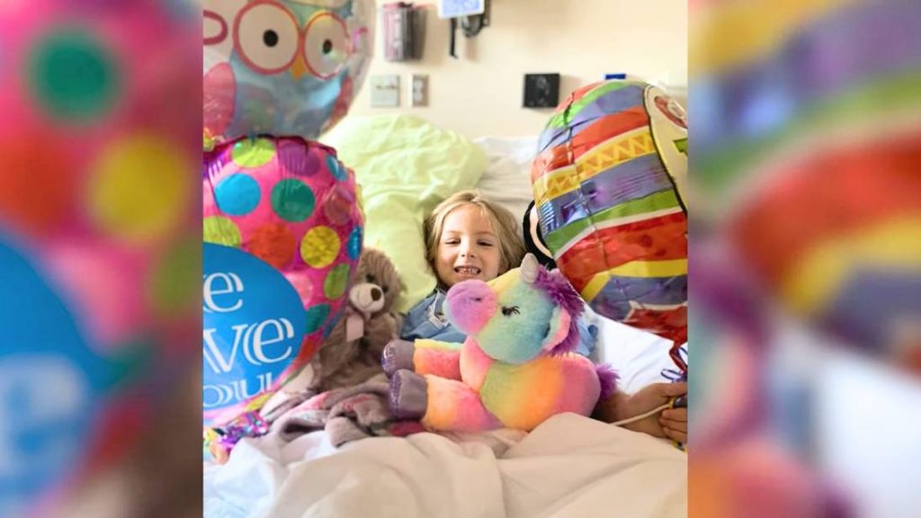 cancer patient Kenedi in hospital bed with stuffed animals