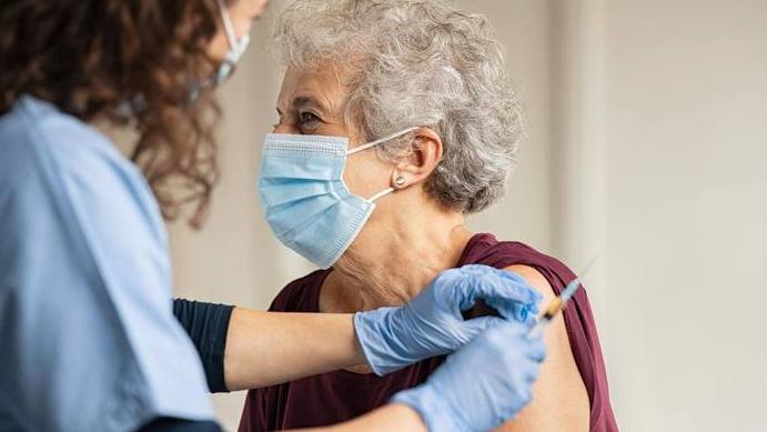 older white woman wearing a face mask and having her COVID-19 vaccine