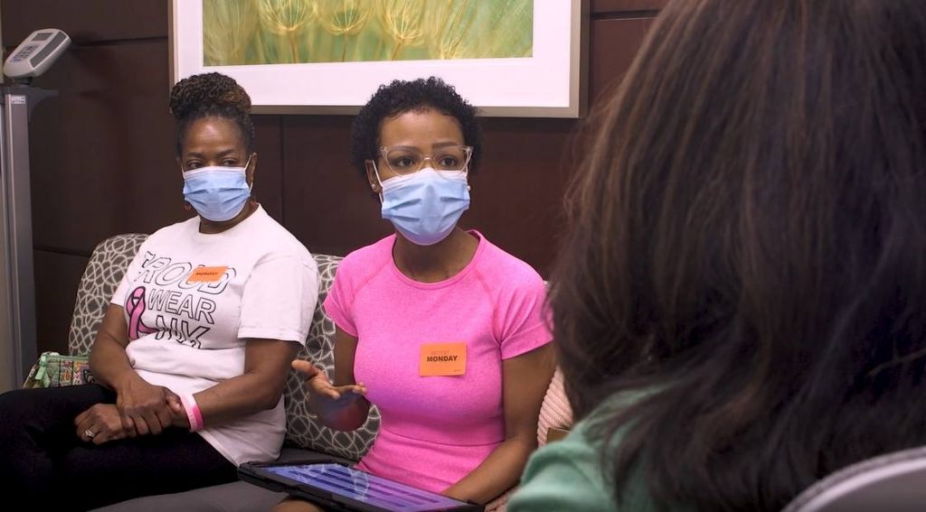 a young Black woman, Jessica Florence, a breast cancer patient, with her mother, both wearing masks, in medical appointment