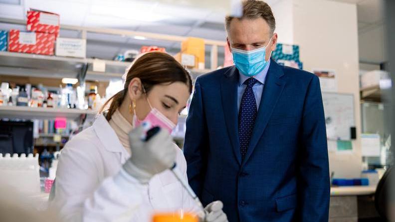 Dr. Andre Terzic observing a colleague in a research lab, both wearing masks