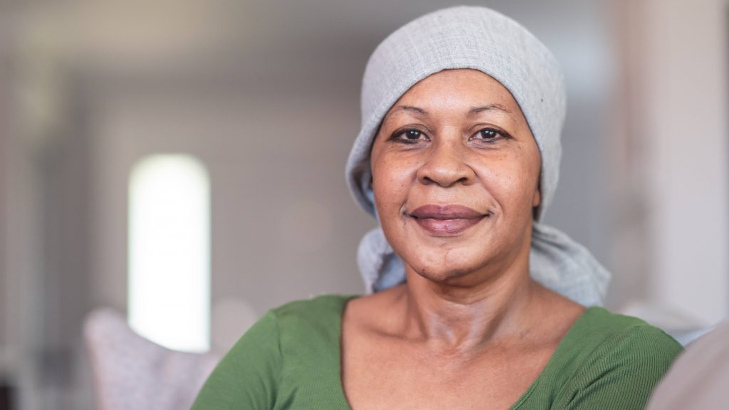 a middle aged Black or perhaps Latina woman, wearing a head scarf because of chemotherapy