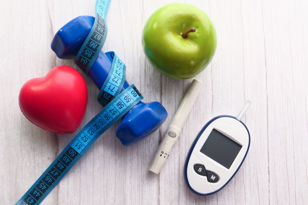 Kits para medir la glucosa sanguínea, pesa de mano y manzana sobre una mesa