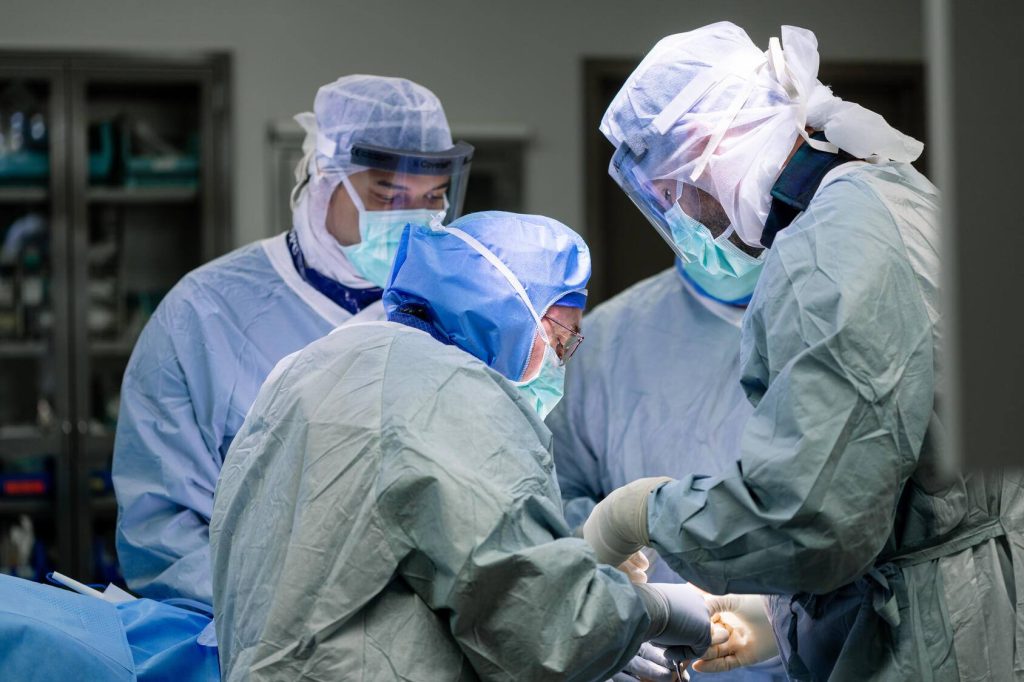 three orthopedic surgeons performing surgery