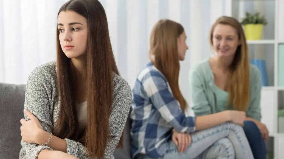 teenage girl being excluded by friends, looking sad and disappointed
