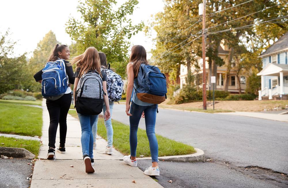 Four-young-teen-girls-walking-to-school-together-backpacks-back-to-school-adolescent