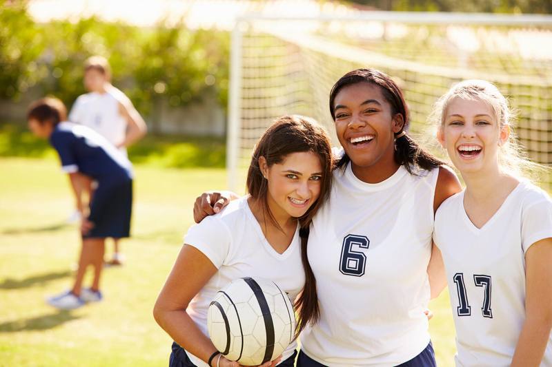three girls, soccer players, smiling