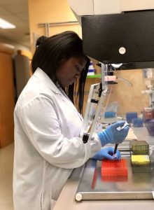 Dr. Abigail Asangba in a laboratory using a pipette