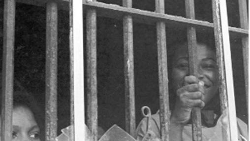 Historical black and white photograph of Shirley Green-Reese as a 13-year-old behind bars as part of the Leesburg Stockade girls