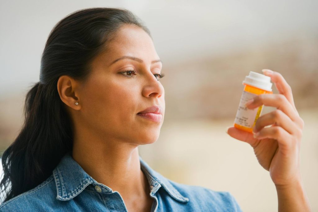 a woman reading the label on a medication bottle