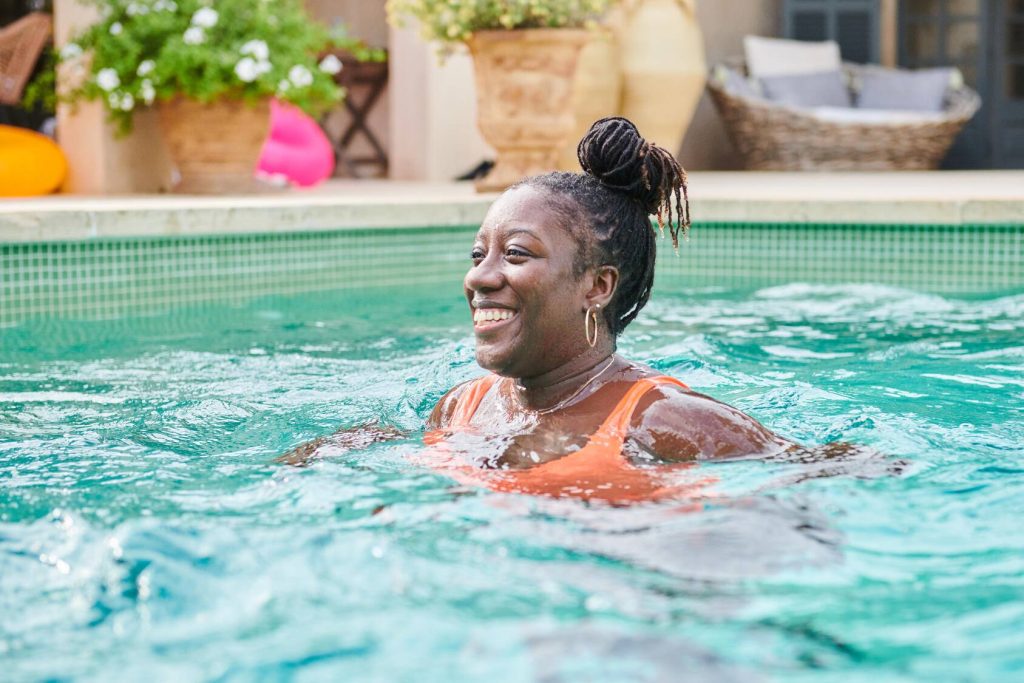 a smiling middle-aged Black woman in a swimming pool