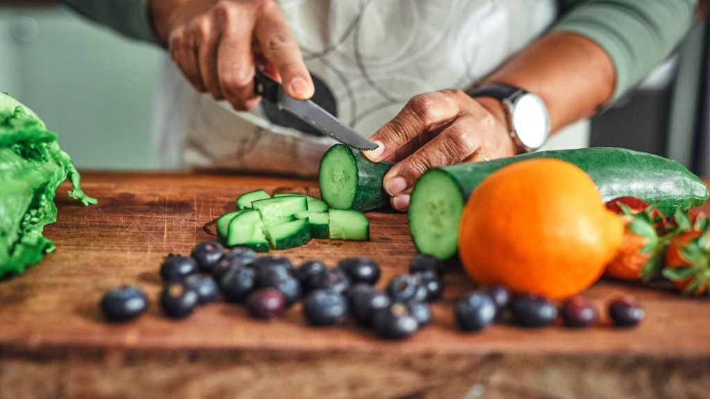 Closeup of man cutting cucumber, vegetables, shot of hands, knife,