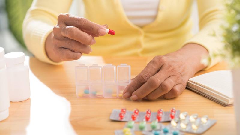 Hands of woman putting pills into pill box