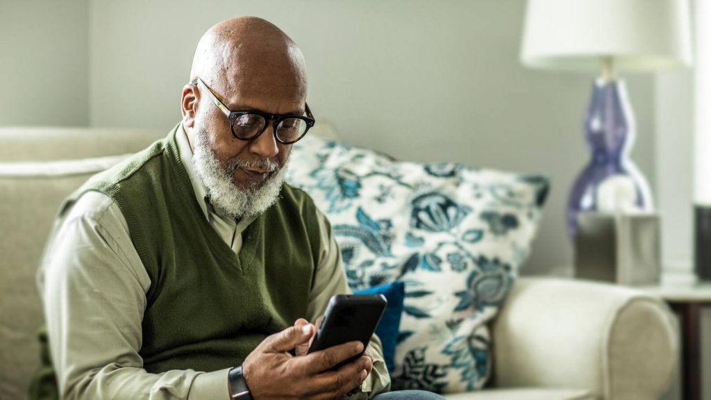 Older man, gray hair, beard, looking at smartphone, social media,